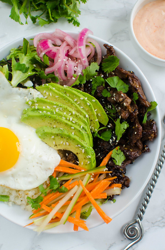 Korean Beef Cauliflower Rice Bowls - delicious sweet and spicy beef with cauliflower rice, veggies, and a fried egg on top! It's paleo but even the non-paleo people in your life will love it!