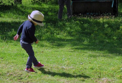 A little girl in a too big hat dances on the grass at the Jumieges Abbey Ruins in France