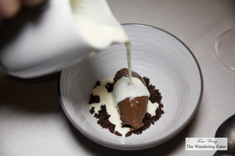 Pouring on the white chocolate sauce onto the chocolate mousse, chocolate cookie cumble