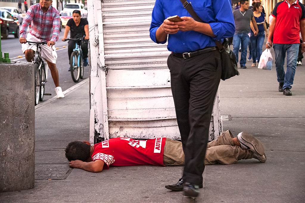 Office worker in front of man lying on sidewalk--Mexico City