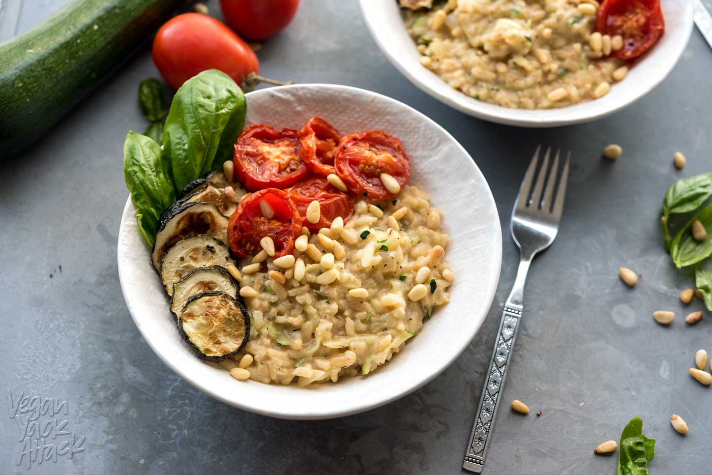 close up of risotto in a bowl topped with roasted zucchini and tomatoes