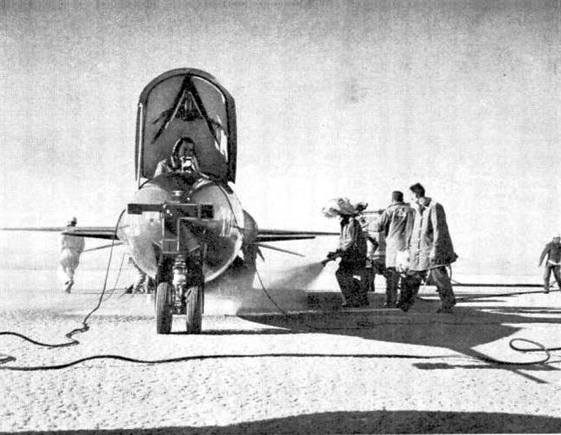 Firemen wash down the landing area in dry lake bed after chemicals were purged from the X-15’s many tanks.
