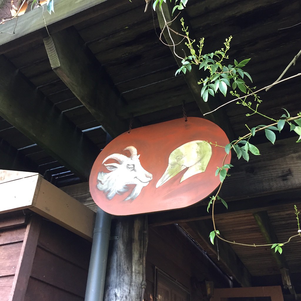 a hanging sign with painted goat and goose head
