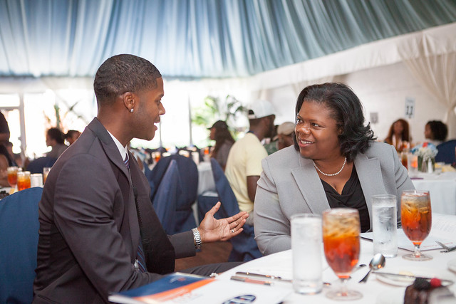 Donovan Livingston and Taffye Benson Clayton talk to each other at a table.