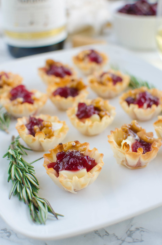 Cranberry Brie Bites - a quick and easy holiday appetizer! Melted brie and cranberry sauce in crisp phyllo cups with candied walnuts on top! 