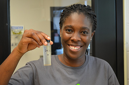 Gifty Acquah holds a sample during a wood chemistry study
