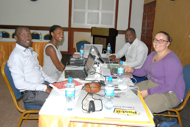Masamu attendees sitting at a table with laptops smiling for the camera