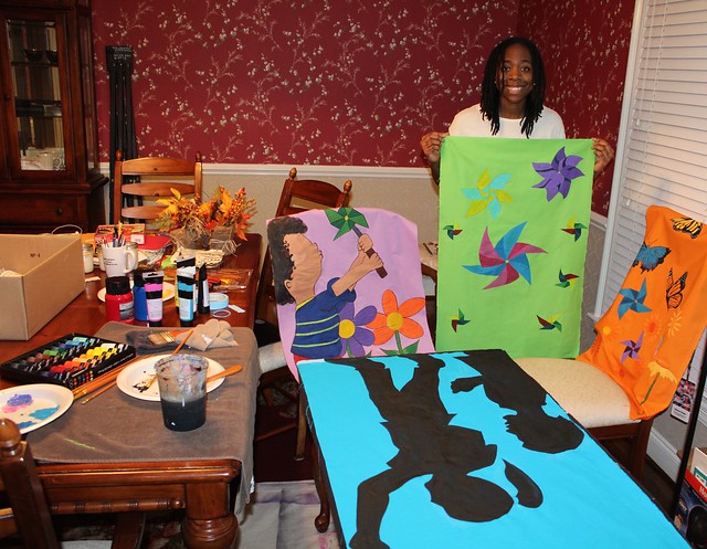 Janelle Green stands amongst her art work and art supplies.