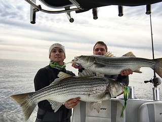 Photo of Joshua and Jeremy Kaltreider holding up two striped bass