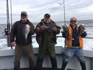 Three men holding their catch of black sea bass