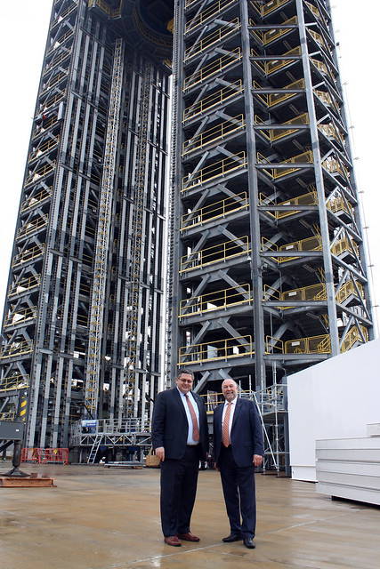 Todd May and Steven Leath stand next to the 221-foot-tall Space Launch System rocket test stand.