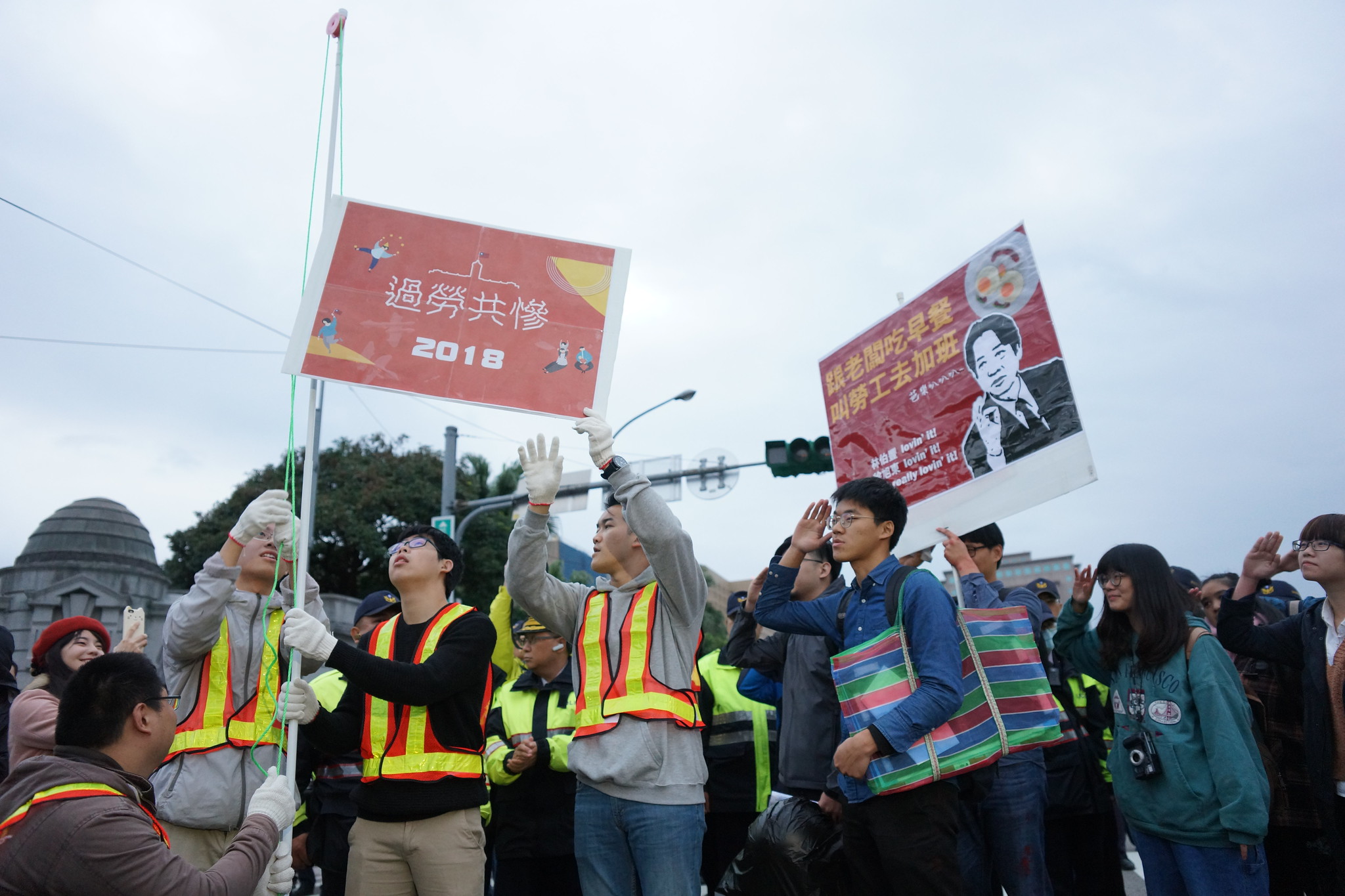 青年勞團的「升旗典禮」旗幟上寫上「過勞共慘」。（攝影：王顥中）