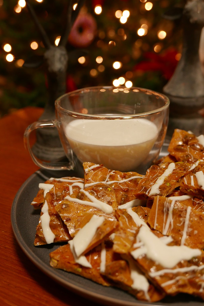 Pistachio Brittle with a cup of milk in front of the Christmas Tree.