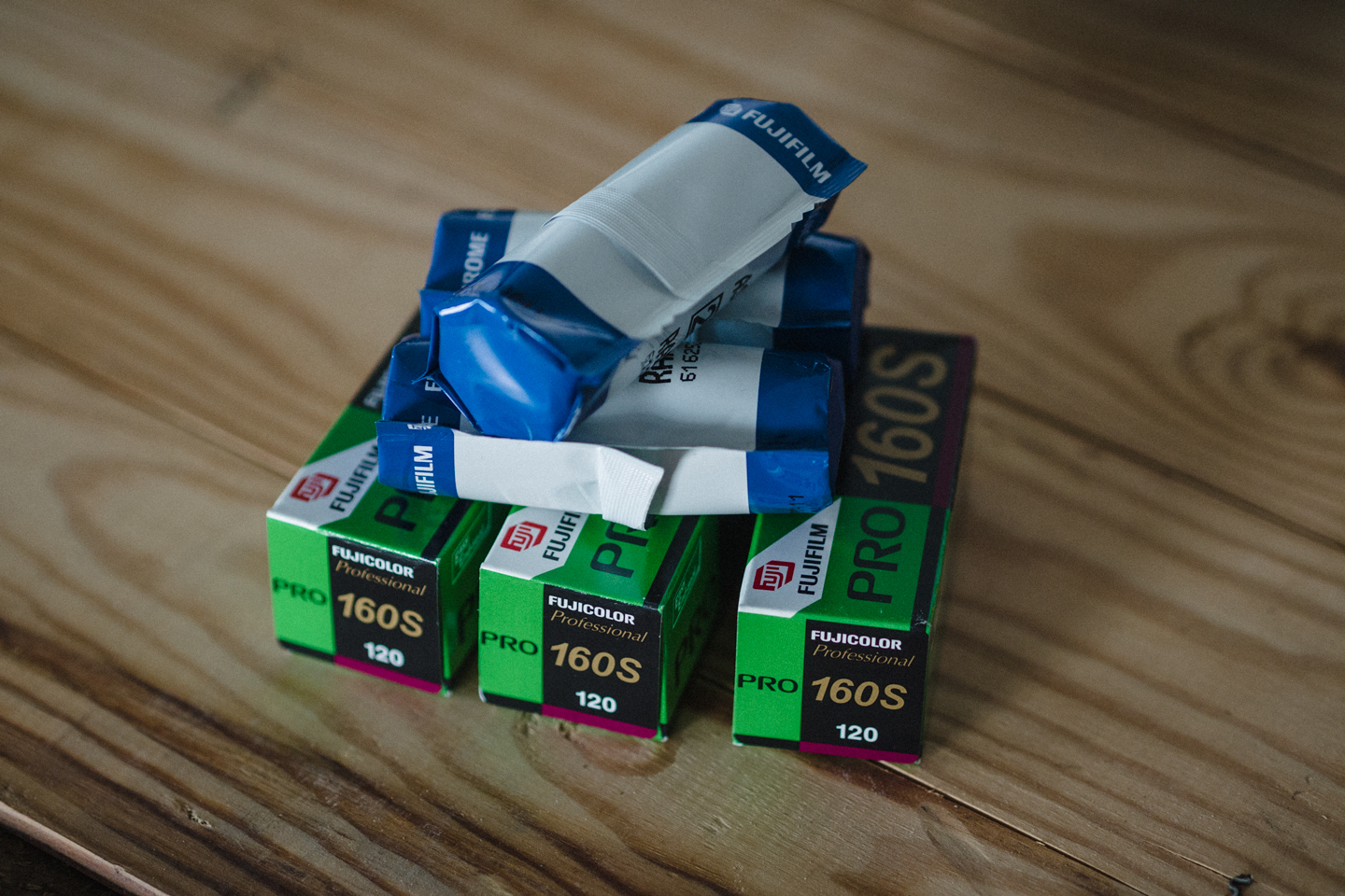 A few Fuji films in 120 and 220 format laying on a wooden box.