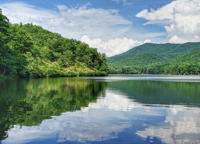 The lake reflects the cloudy skies and mountains at Douthat State Park, Va