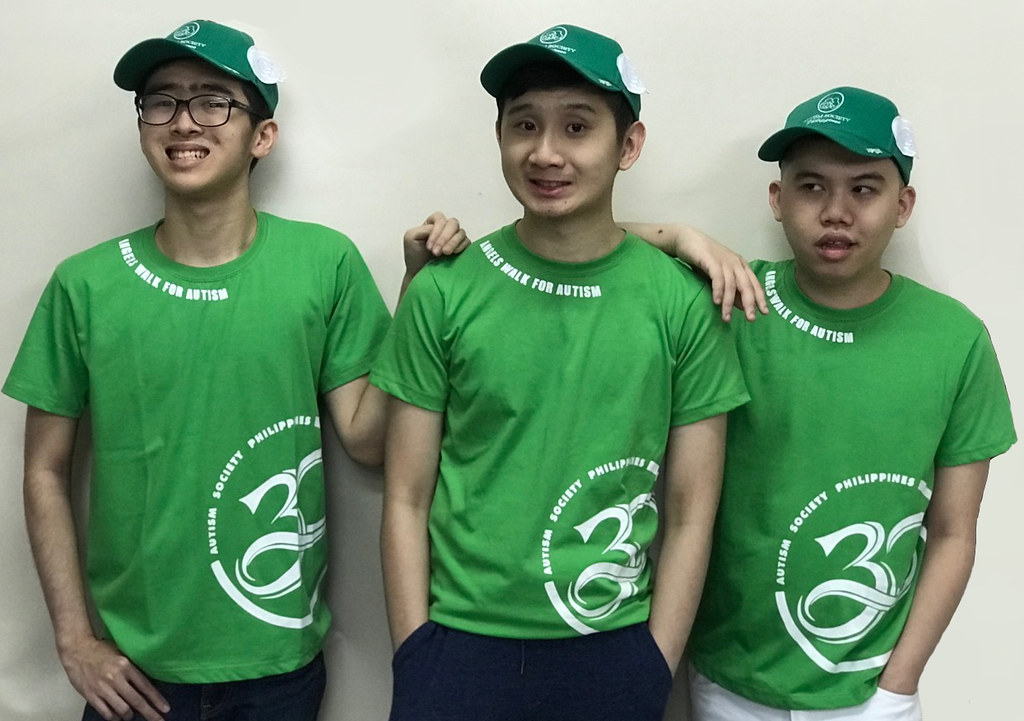 The image shows three PWA boys wearing 2019 Angels Walk shirt with "Autism Society Philippines" below the right neck shirt and "30" at the left side of the shirt. They also wear a green cap with white wings in both sides.