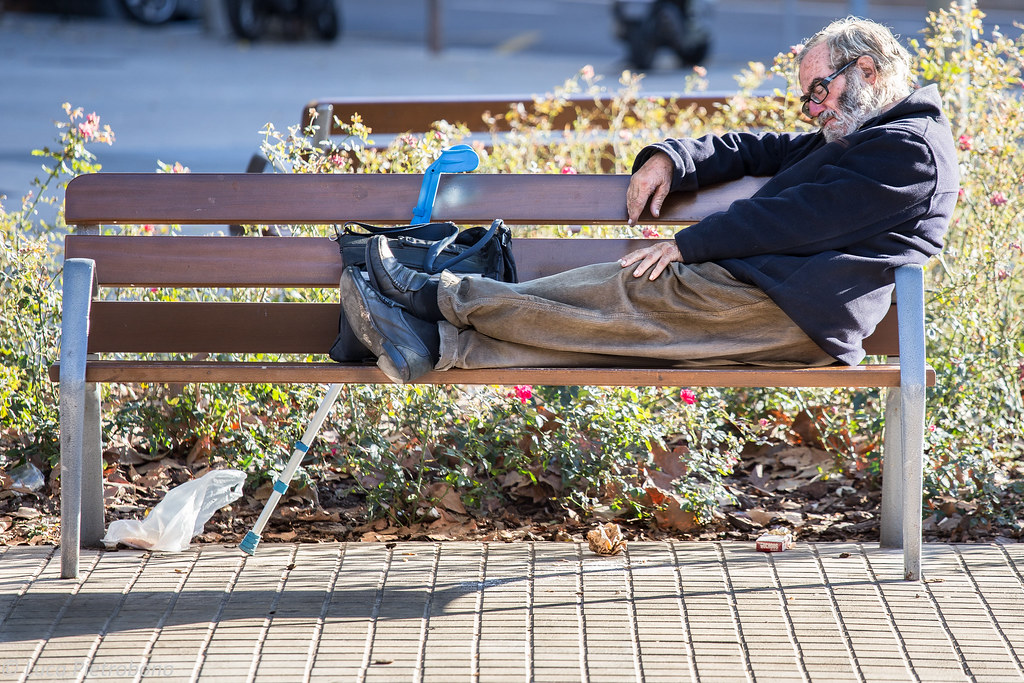 Homeless man sitting on a New York bench. One of the interesting facts about New York is how the state pays for the relocation of the homeless.