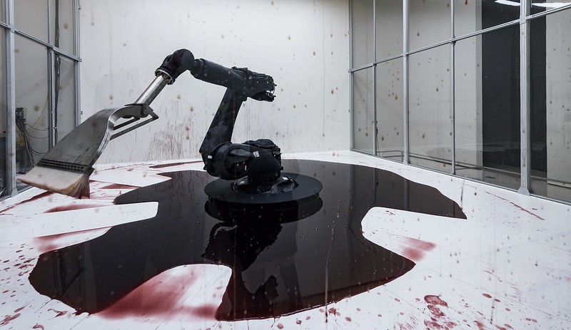 A Large Robotic Arm Futilely Tries to Clean a Blood Red
