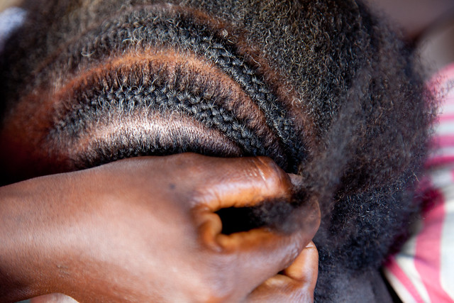 With nimble fingers a young teenage girl, cornrows the hair of her sister in the village of Cestos in Rivercess County Liberia.