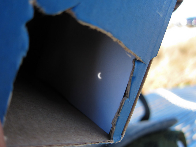 A picture showcasing the viewfinder part of a shoebox pinhole projector, where we see an image of a solar eclipse.