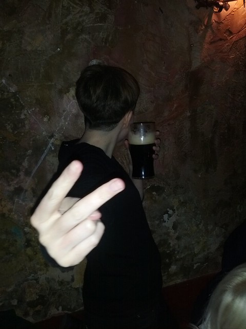 Photo of Natasha with her back to the camera, drinking a pint, giving a v-sign