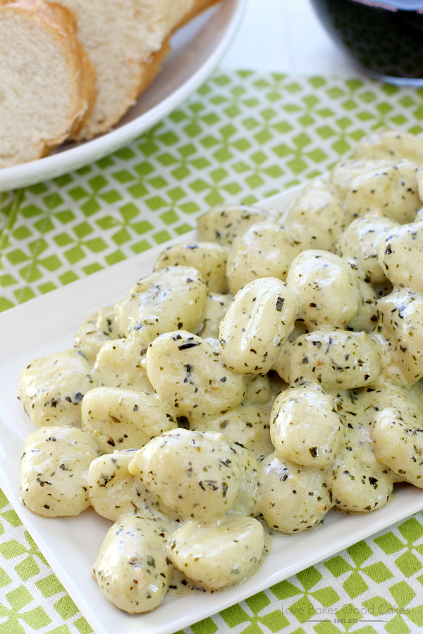 Gnocchi with Pesto Cream piled up on a plate with slices of bread.