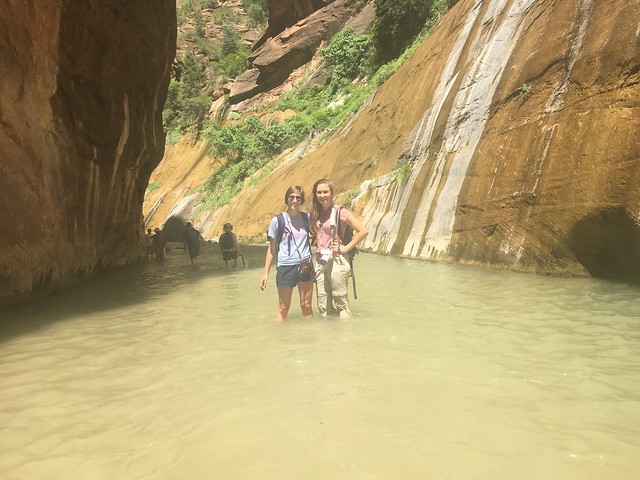 Two women standing in the water of the narrows at Zion National Park.