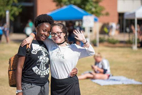 Two female students wave hello on Hey Day.