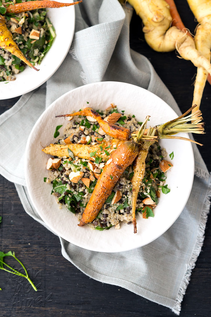 White bowl with mixed grains/legumes topped with roasted carrots on a folded linen