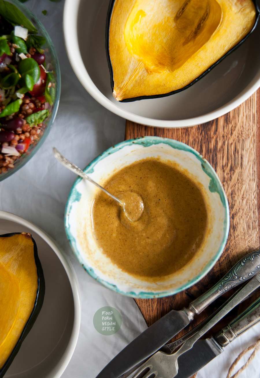 Roasted acorn squash stuffed with sorghum grains and vegetables, topped with an indian tahini sauce