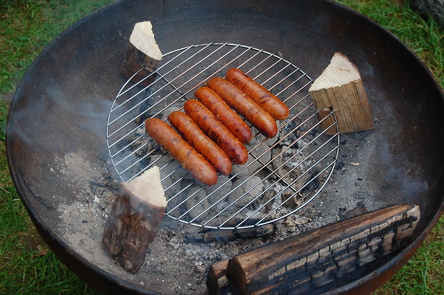 Sausages on grill, held up by three wooden blocks