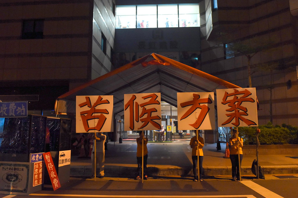收費員在民進黨中央黨部前舉牌抗爭。（攝影：宋小海）