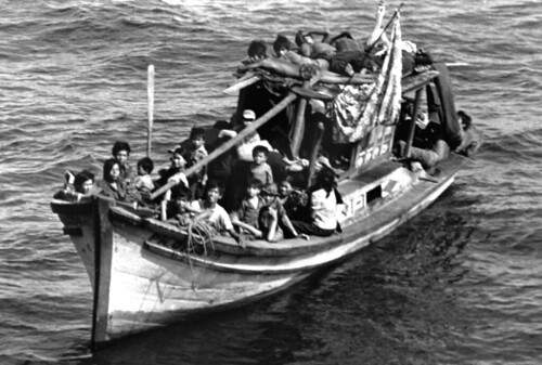 Port bow view of a boat filled with Vietnamese refugees, as the guided missile cruiser USS FOX (CG-33) (not visible) comes alongside