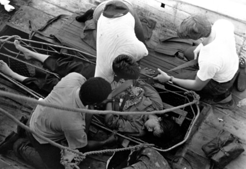Crewmen from the USS FOX (CG-33) prepare to hoist a female Vietnamese refugee aboard the guided missile cruiser.