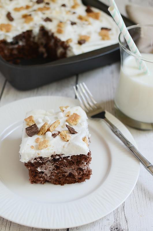 S'mores Poke Cake - chocolate cake with marshmallow sauce inside! And topped with Cool Whip, crushed graham crackers, Hershey's bars, and marshmallows!