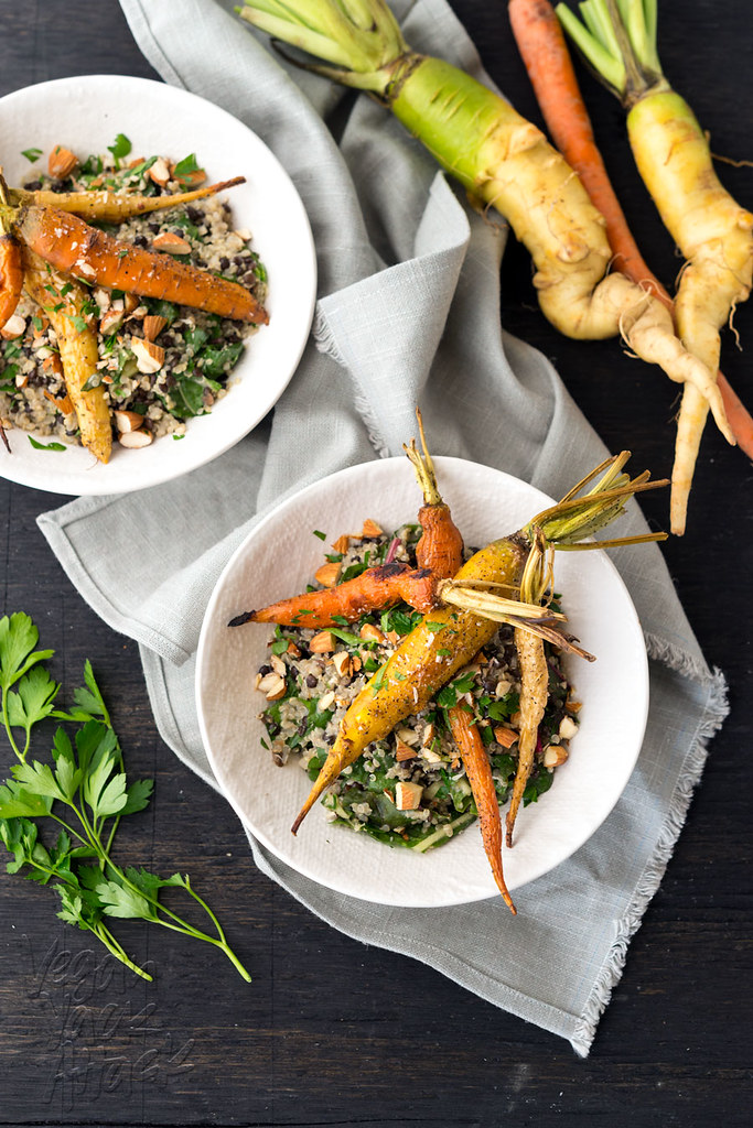 White bowls with mixed grains/legumes topped with roasted carrots on a folded linen