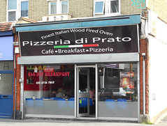 The same shopfront as above, with the posters removed and a new sign over the previous one, this one reading: “Finest Italian Wood Fired Oven / Pizzeria di Prato / Café · Breakfast · Pizzeria”.