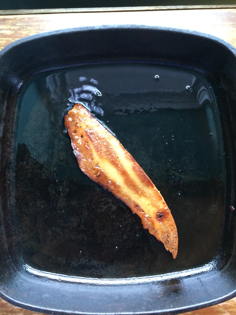 slice of bacun frying in a pan
