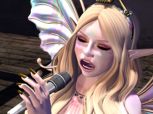 Image Description: Closeup of a woman holding a microphone and singing with her eyes closed.