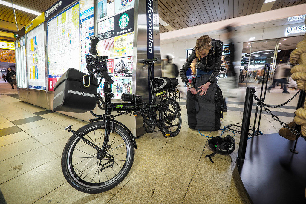 Packing up a Tern folding bicycle for train travel in Sapporo station, Japan